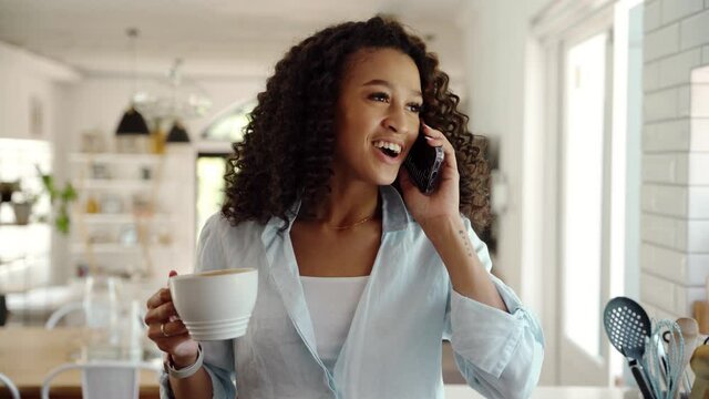 Mixed race female working from home chatting on cellular device drinking hot coffee