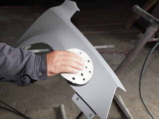 Manual dry sanding a car body part with abrasive paper before painting, vehicle body repair service