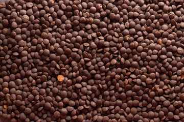 background of red lentils. scattered lentils. one split lentils against a whole background