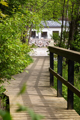 Wooden walkway and an old building by the River Vantaa at the Vantaankoski nature trail  in Vantaa, Finland, on a sunny day in the summer.