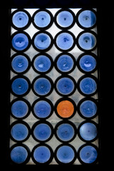 Antique window with many blue round glass and one orange glass