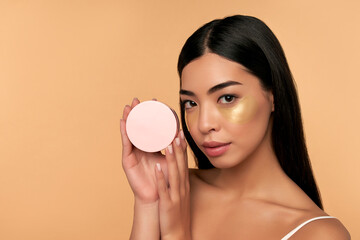 Young Asian woman in white lingerie and clean radiant skin with moisturizing patches under the eyes...
