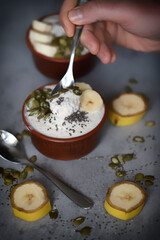 Male hands with a spoon of yogurt. Healthy chia yogurt with seeds and banana.