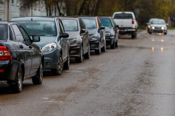 cars parked on side of wet dirty road - telephoto close-up with selective focus