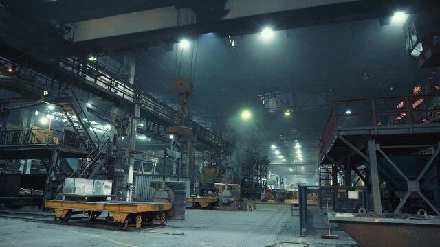 Large industrial dark workshop with moving beam crane and hook of metallurgical plant, industry background.