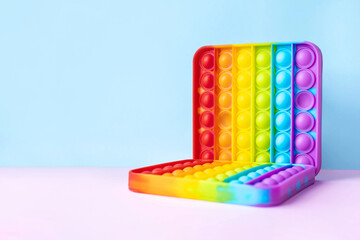 Colorful anti-stress fidget push pop it sensory toy for children isolated on blue and pink background. Simple dimple. Top view, flat lay. Selective focus.