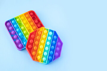 Colorful anti-stress fidget push pop it sensory toys for children isolated on blue background. Simple dimple. Top view, flat lay, copy space. Selective focus.