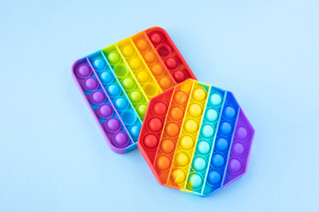 Colorful anti-stress fidget push pop it sensory toys for children isolated on blue background. Simple dimple. Top view, flat lay. Selective focus.