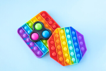 Colorful anti-stress fidget push pop it sensory toys for children isolated on blue background. Simple dimple. Top view, flat lay. Selective focus.