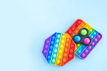 Colorful anti-stress fidget push pop it sensory toys isolated on blue background. Simple dimple. Top view, flat lay, copy space. Selective focus.