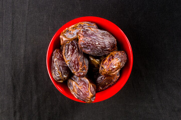 Big luxury dried date fruit in bowls on the dark surface, kurma ramadan kareem concept, close up.