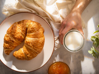 Wonderful morning breakfast with croissants, jam and milk. Beautiful white dishes. Pastel background. Bright lighting. High angle view. View from above. Close-up.