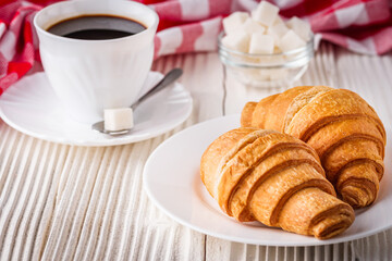 delicious fresh croissant and cup of coffee on a white wooden rustic background