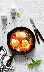 Shakshuka in a frying pan on the kitchen table. Dish of eggs, tomatoes and peppers, onions. Breakfast with vegetables and eggs..