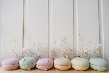 Fototapeta na wymiar Macarons of different colors lie on a light wooden background. The decor is made of white gypsophila flowers. Place for your text.