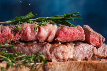 In the photo we see an appetizing chop cutlet on a piece of bread. From above it is decorated with sprigs of fresh greenery. Dark blue background. Close-up. Macro photography.