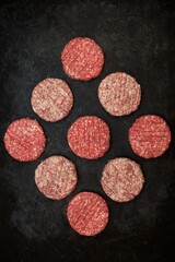 Obraz na płótnie Canvas Raw Minced Steak Burgers from Beef and Pork Meat on Black Background, Overhead View. Raw Ground Beef, Round Patties for Cooking Homemade Burger On BBQ Grill, Top View