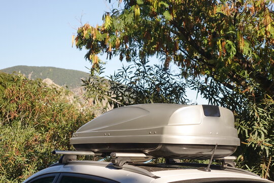 Car Trunk Box On Roof. 4WD Car With Luggage Box On Rooftop Fastening To The Rack System. Closeup View Of Car Roof Box On Rooftop. Travel And Trip Auto Tourism Landscape With Mountain And Sea Beach.