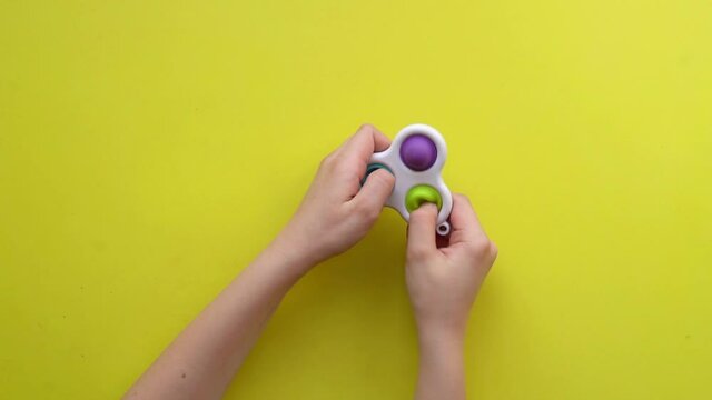 Popit antistress toy for children entertainment on a yellow background playing a child top view in colored fijit simple dimple popit fidget, tress sensory bubble bubble ubble, Top otor , poppit