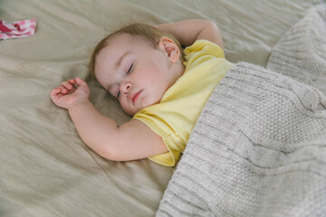 Baby one-year-old sleeping in the bedroom on the bed