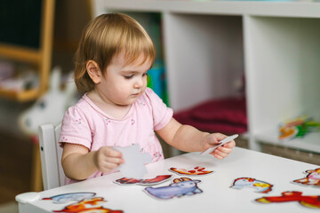 One and a half year old girl collects puzzles. Psychomotor skills and the development of logical thinking
