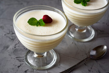 Delicate dessert: panna cotta with berries and mint in a beautiful cream bowl