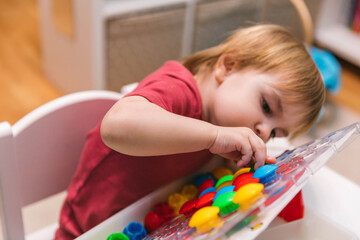Two-year-old child plays with mosaics, fine motor skills development