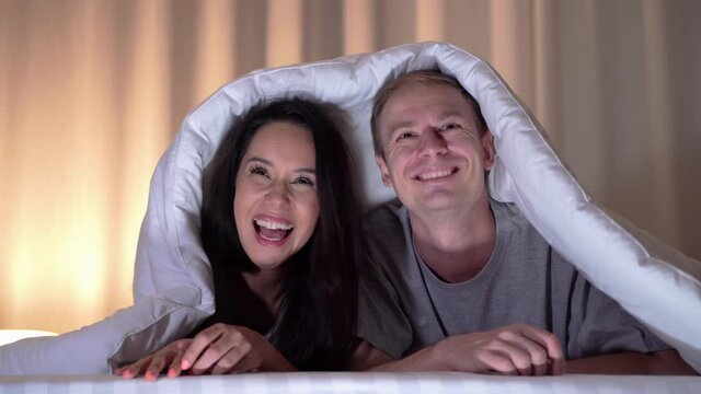 Couples are sleeping and watching series in our bed, Couples laughing happily during their vacations at night.
