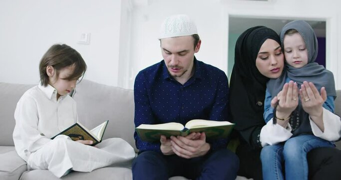 Muslim family reading Quran and praying together on the sofa