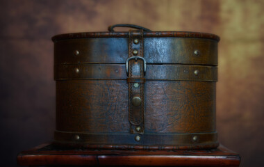 Side view of an ancient brown leather jewelry box on a wooden table