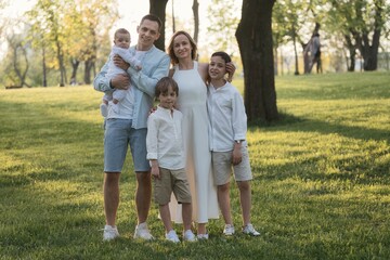 Naklejka na ściany i meble Happy family with three male children posing in park