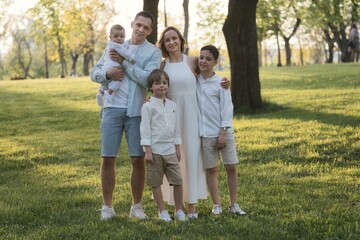 Naklejka na ściany i meble Happy harmonious family with three kids outdoors. Family portrait in park