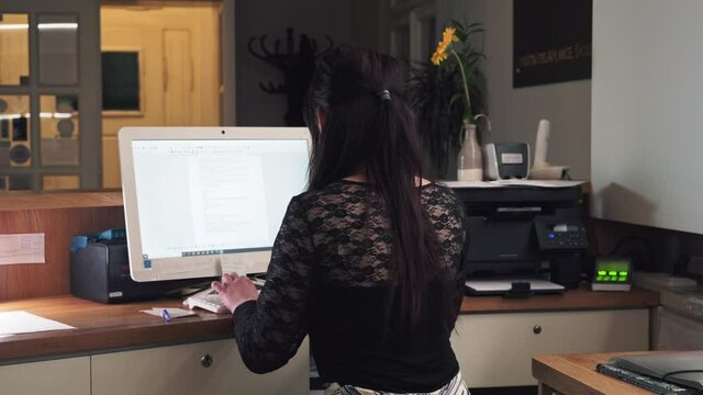 Girl at hotel reception using computer, writing keyboard, back midle shot view