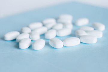 White pills on a light blue background. Healthcare and medicine.