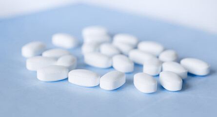 Fototapeta na wymiar White pills on a light blue background. Healthcare and medicine.