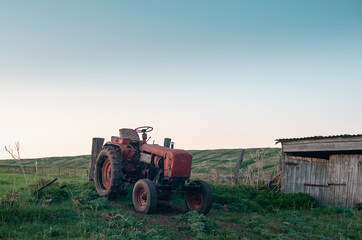 Obraz premium Old tractor near the barn at sunset.