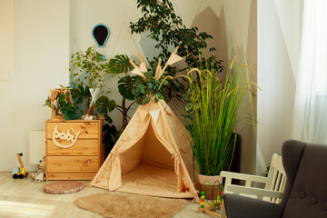 interior of a children's room or recreation area: a wigwam with soft pillows, a wooden nightstand made of environmentally friendly materials. plastic plants to decorate the space © skeronov