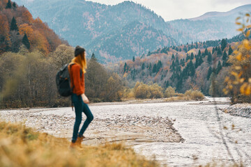 Naklejka premium woman travels in autumn in the mountains near the river landscape model in full growth