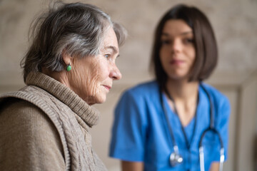 Young nurse is caring for an elderly 80-year-old woman at home, helping her and giving her treatment recommendations. Happy retired woman and trust between doctor and patient. Medicine and healthcare.