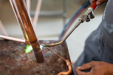 Close up on hands of unknown industrial worker plumber with central heating copper pipes welding...