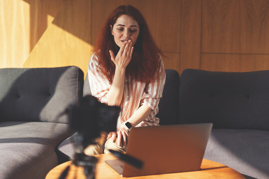 Successful blogger woman recording stream with digital camera, tripod and laptop