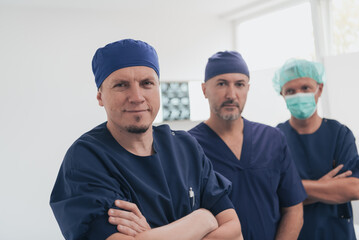 Multiethnic orthopedic doctor in front of his medical team looking at camera wearing face mask 