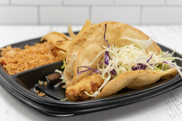 Two kinds of tacos served with all the fillings, rice, and refried beans as a combination plate