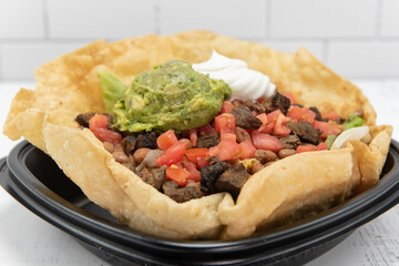 Steak taco salad served in a crispy tostada bowl, topped with sour cream and guacomole, will fill your appetite perfectly