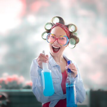 Young woman with curlers in her hair cleans a window with rag and wiper in hand