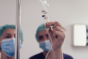 General practitioner holding intravenous drip infusion. Doctor handling IV fluid drip with copy...