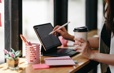 Businesswoman working on digital tablet with a stylus at cafe. Female entrepreneur checking few financial reports on her tablet computer