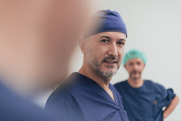 Multiethnic orthopedic doctor in front of his medical team looking at camera wearing face mask 