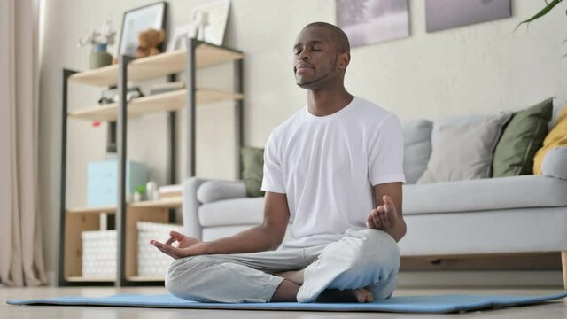 Young African Man Meditating on Yoga Mat at Home
