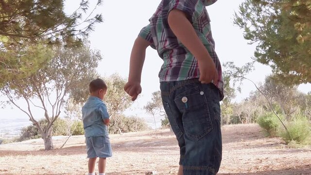 Siblings playing in the nature. Exploring the dirth and dry grass on sunny summer day throwing the rocks. High quality FullHD footage